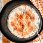 creamy Hungarian cucumber salad recipe in a black serving dish sprinkled with Hungarian paprika
