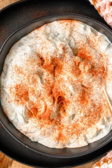 creamy Hungarian cucumber salad recipe in a black serving dish sprinkled with Hungarian paprika