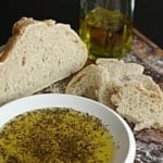 italian dipping oil for bread on a white ceramic plate next to a loaf of sourdough bread