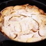 german apple pancake dusted with confectioners sugar in a cast iron skillet