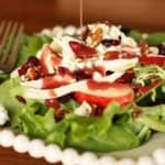 pomegranate salad dressing being drizzled over a copycat Wendy's pecan apple salad