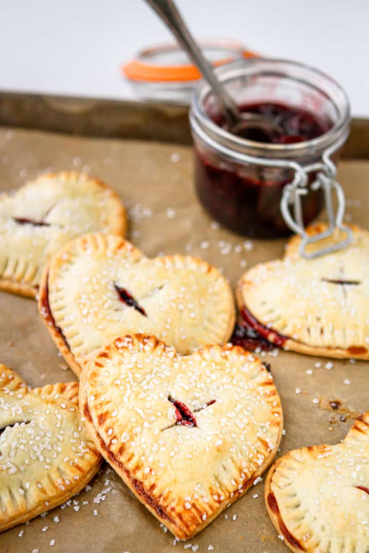 cherry-filled hand pies stacked with a jar of cherry filling