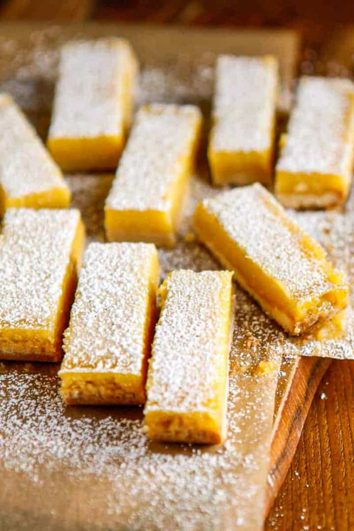 cut lemon bars dusted with powdered sugar on brown parchment paper