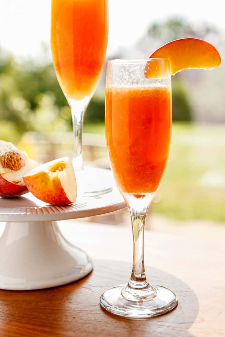 frozen peach bellini cocktail with a slice of fresh peach on the rim