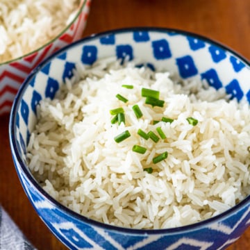 coconut milk rice in a blue and white bowl garnished with chopped chives