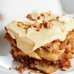 caramel buttercream frosting on top of a slice of fresh apple cake topped with toasted chopped pecans