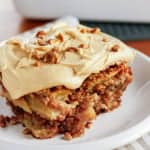fresh apple cake topped with caramel buttercream frosting and toasted chopped pecans