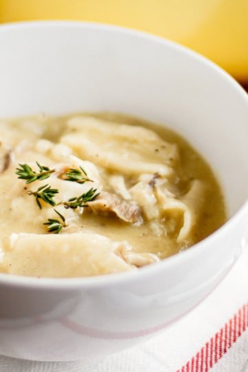 rotisserie chicken and dumplings in a bowl with fresh thyme sprinkled over top