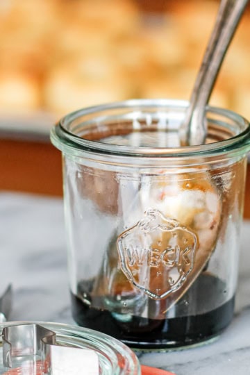 balsamic reduction in a small glass weck jar with a silver spoon resting in it