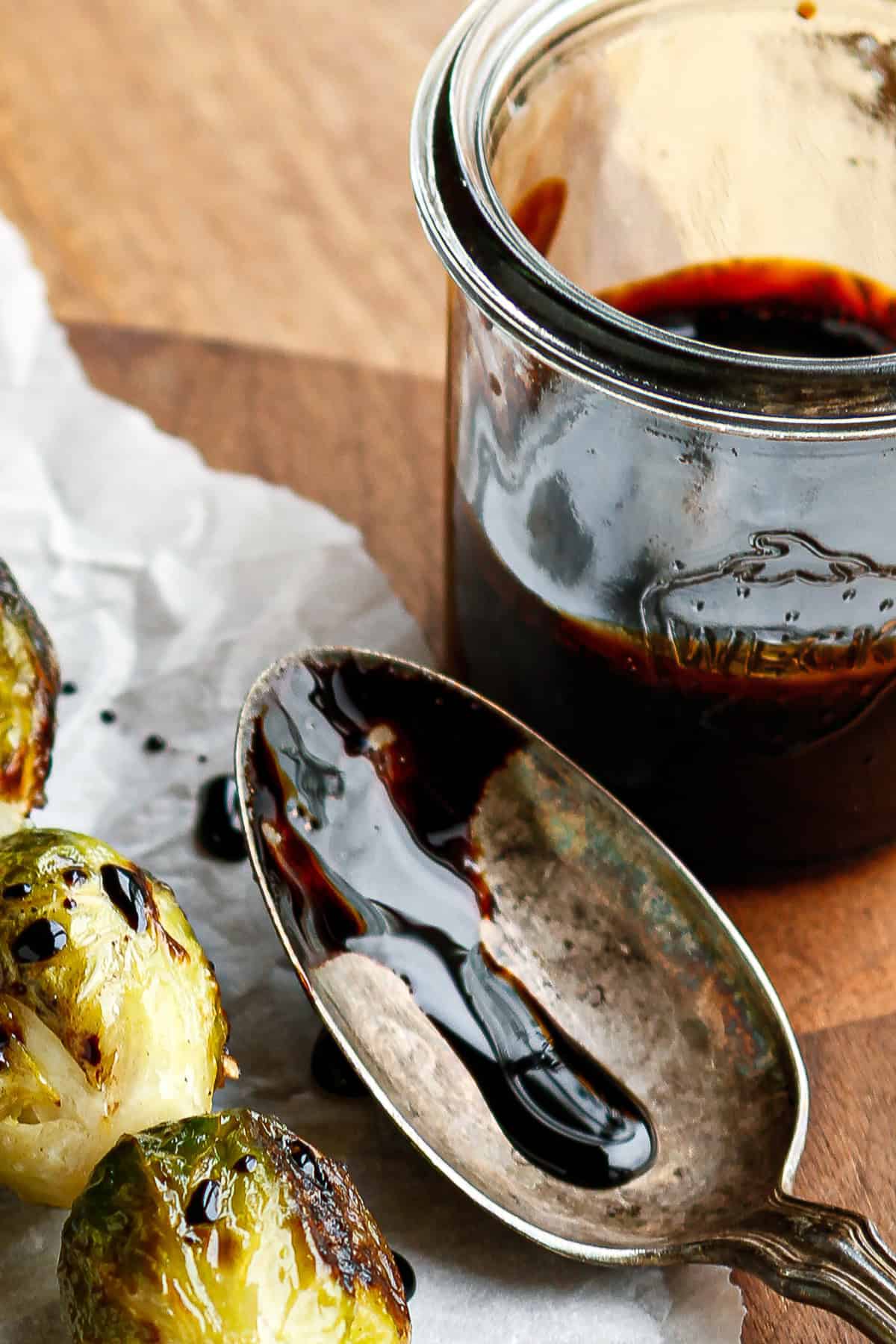 reduced balsamic vinegar on a silver spoon with grilled Brussels sprouts