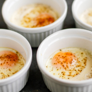 baked eggs in white ramekins on a baking sheet