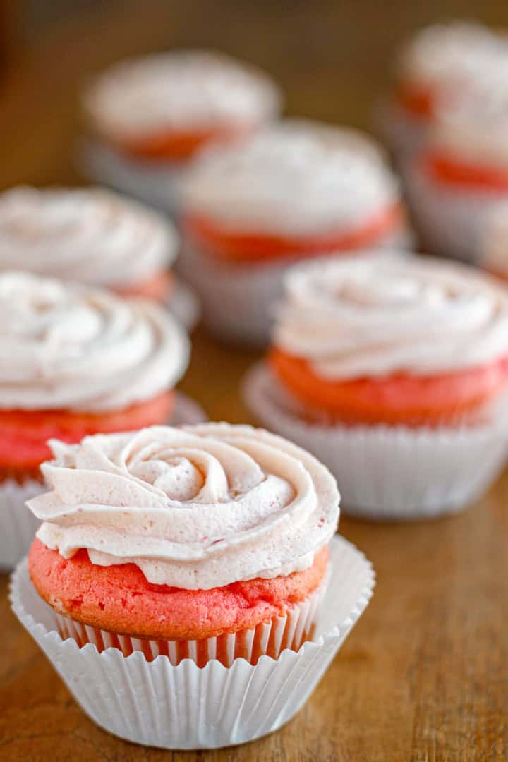 fresh strawberry buttercream frosting piped on pink velvet cupcakes in a swirl pattern