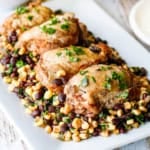 cilantro lime chicken thighs with corn and black beans on a white platter