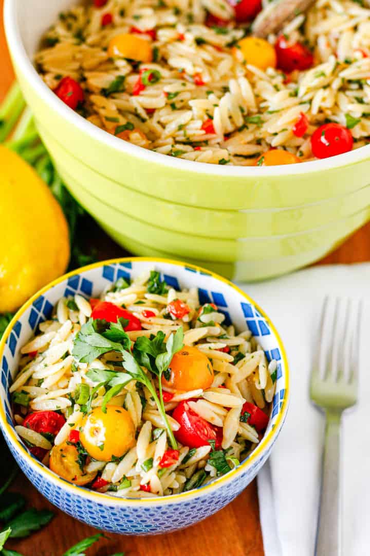 lemon orzo pasta salad packed with veggies in a blue ceramic bowl with a yellow rim
