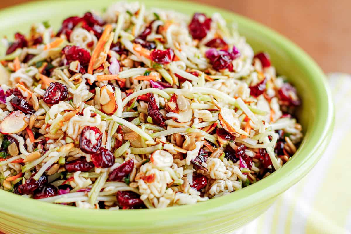 broccoli coleslaw salad with ramen noodles in a bright green ceramic bowl
