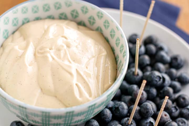 cream cheese fruit dip in a ceramic bowl surrounded with fresh blueberries