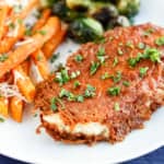 parmesan crusted chicken breast on a plate garnished with fresh parsley