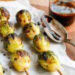 grilled brussels sprouts on bamboo skewers drizzled with balsamic glaze