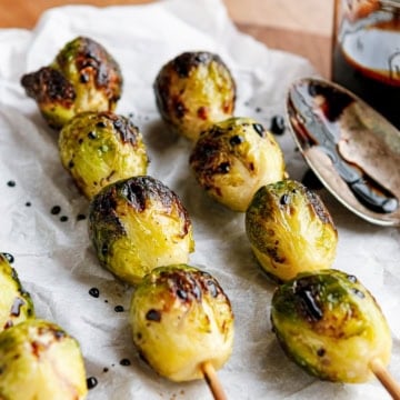 grilled brussels sprouts on bamboo skewers drizzled with balsamic glaze