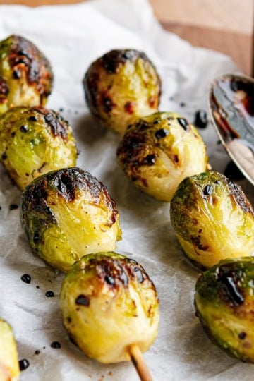 grilled brussels sprouts on bamboo skewers drizzled with balsamic glaze