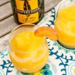 wine slushie recipe in an acrylic wine glass with a fresh peach garnish