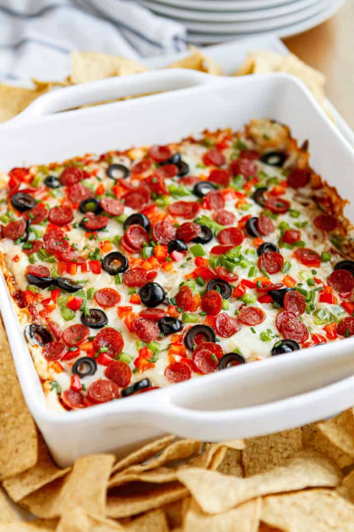 pepperoni pizza dip in a white baking dish surrounded by tortilla chips