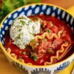 easy lasagna soup recipe in a blue and white bowl garnished with a creamy ricotta Parmesan topping and parsley
