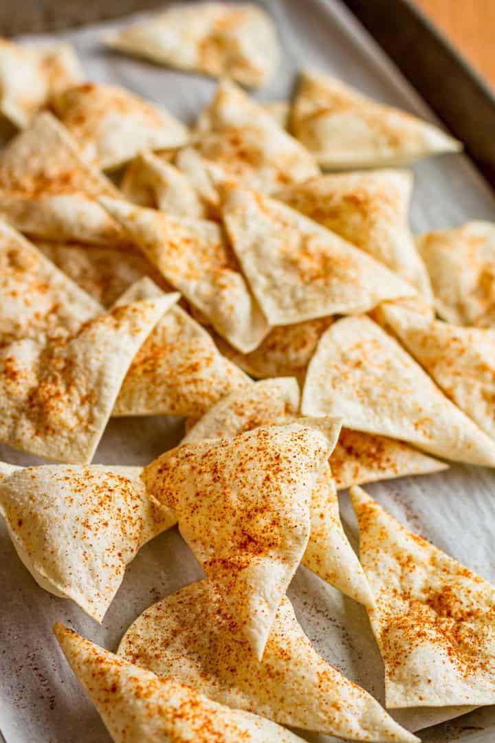 baked tortilla chips sprinkled with chili powder on parchment paper
