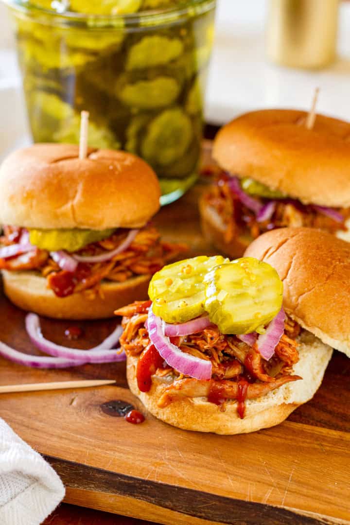 bbq chicken sliders with rotisserie chicken garnished with sliced red onions and sweet pickles