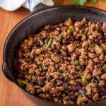 ground beef taco meat with black beans in a cast iron skillet garnished with chopped cilantro