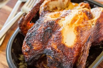 whole rotisserie chicken in plastic tray ready to cut