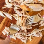 hands demonstrating how to shred rotisserie chicken with two forks