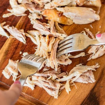demonstrating how to shred rotisserie chicken with two forks