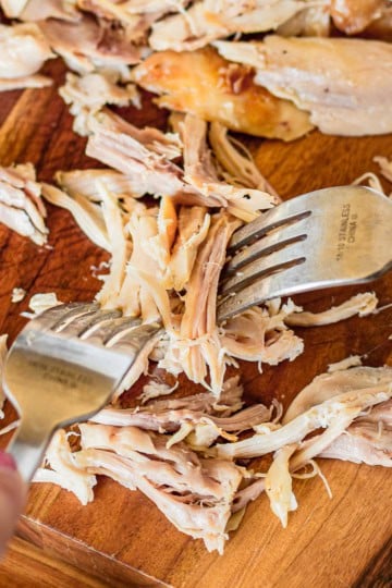 demonstrating how to shred rotisserie chicken with two forks