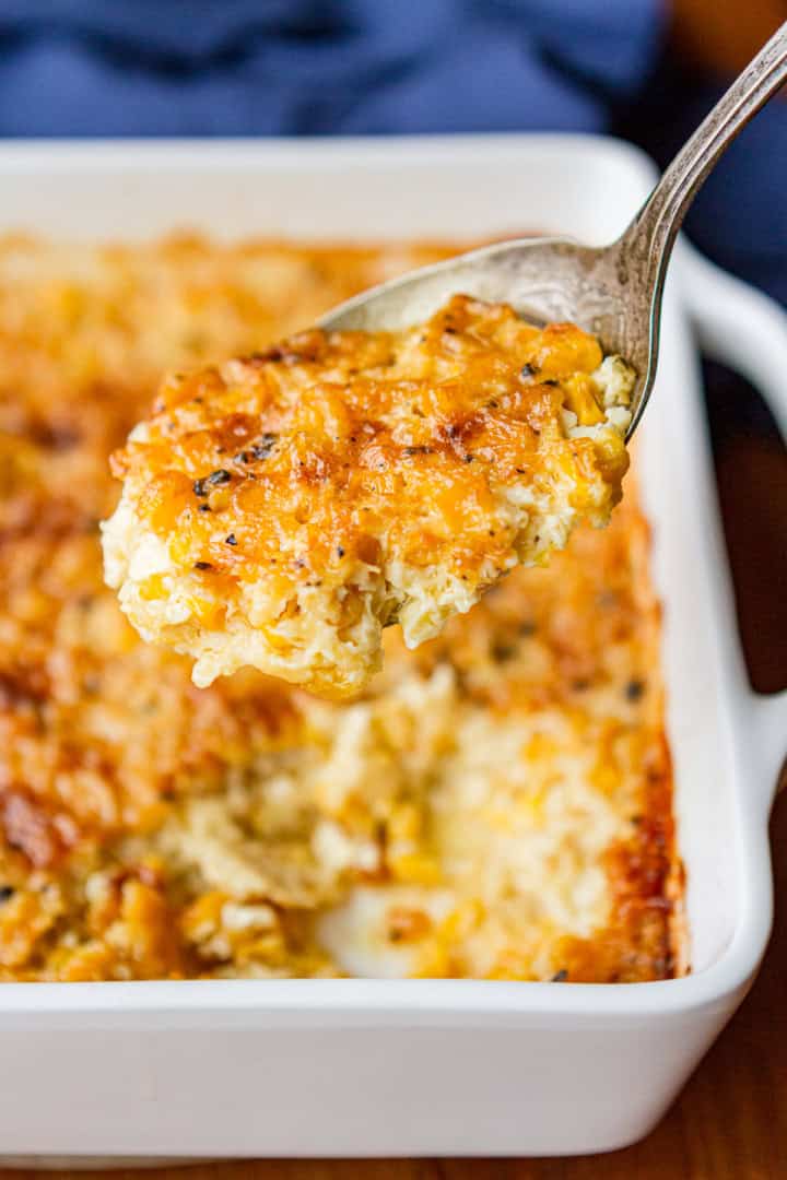 cream corn casserole being scooped out with a large antique spoon aka corn pudding or custard corn