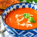 creamy tomato basil soup recipe garnished with cream and fresh basil