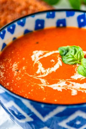 creamy tomato basil soup recipe garnished with cream and fresh basil