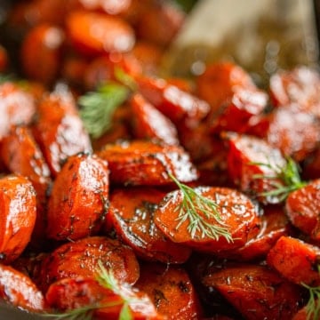 honey roasted carrots garnished with fresh dill in a black iron skillet