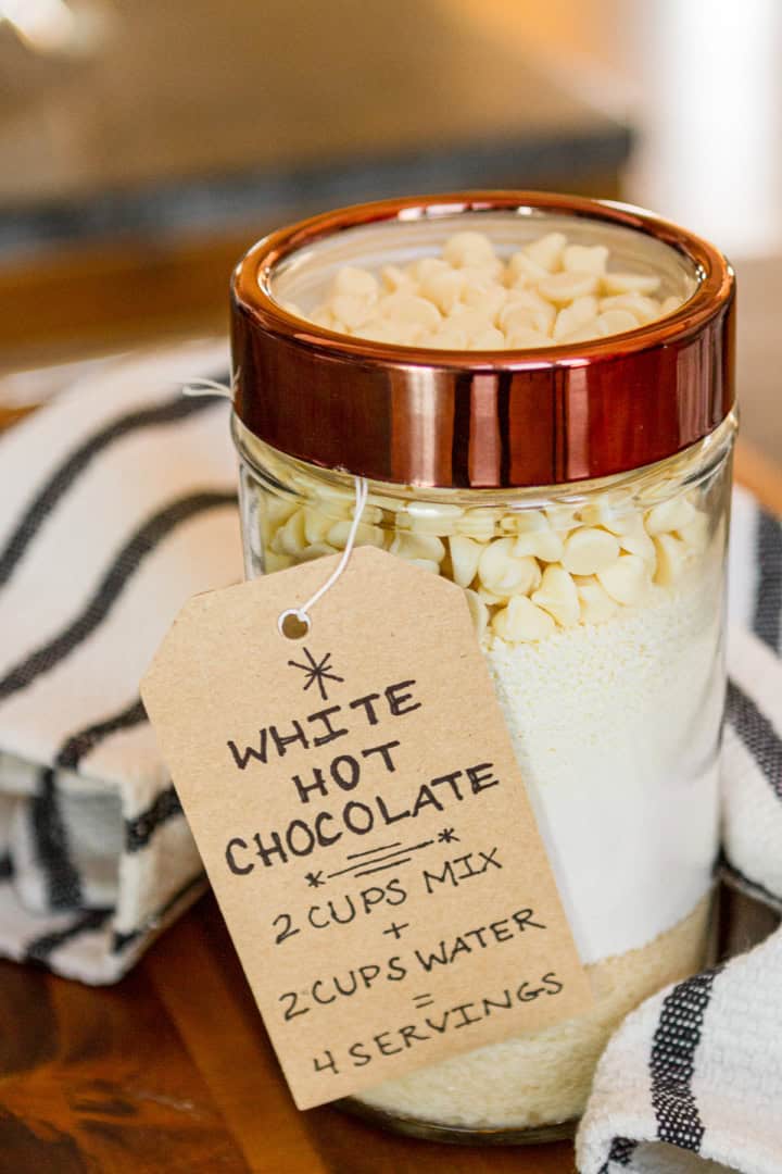 glass jar filled with white hot chocolate mix with a brown paper instructions tag