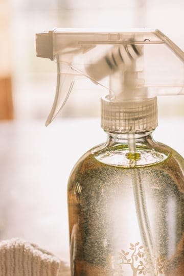 homemade glass cleaner recipe in a glass spray bottle with a microfiber cloth