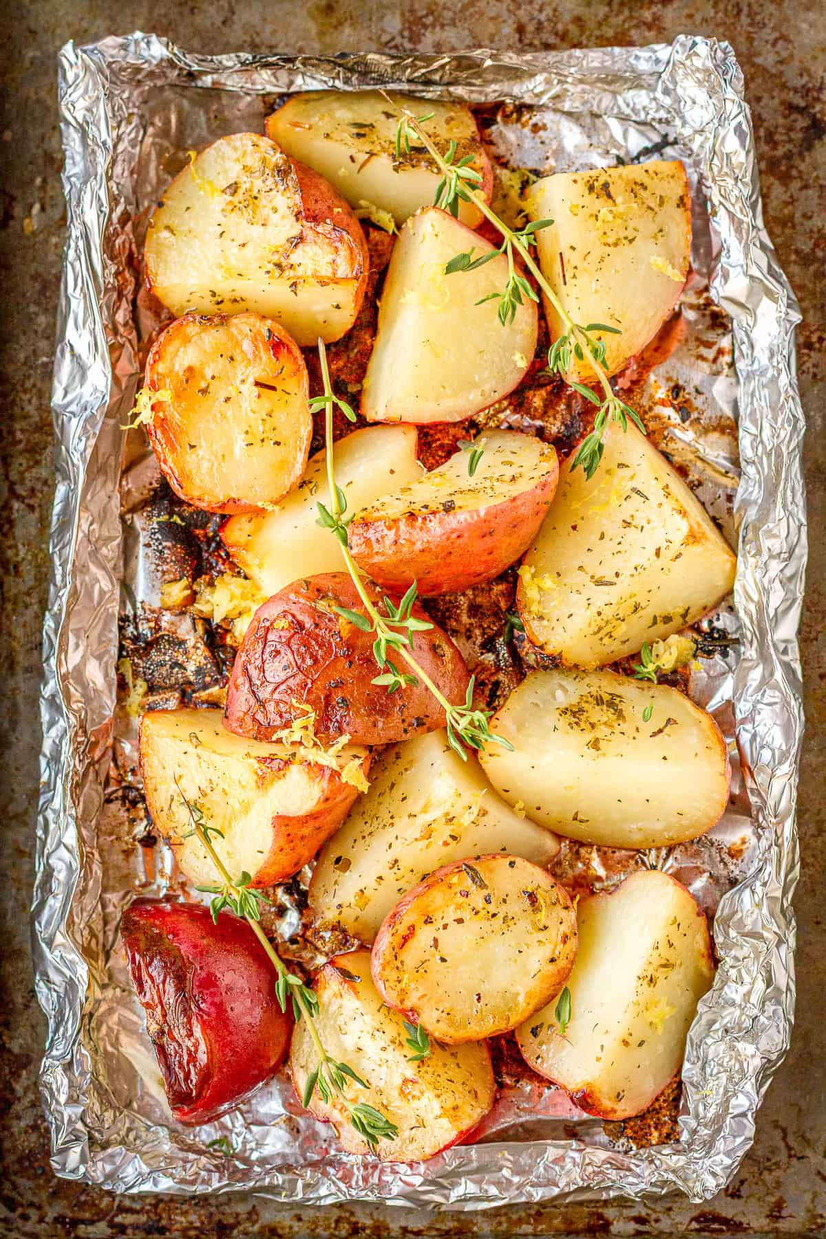 grilled baby red potatoes in a foil packet topped with fresh thyme and lemon zest