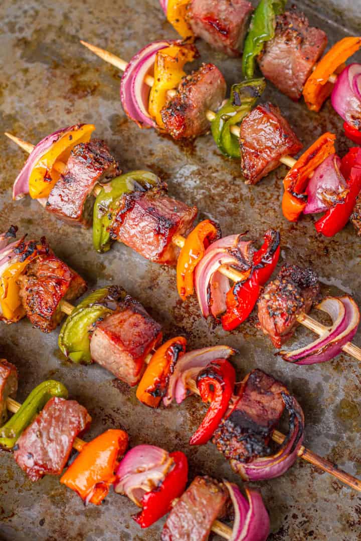 grilled tri-tip kabobs with peppers and onions on a baking sheet