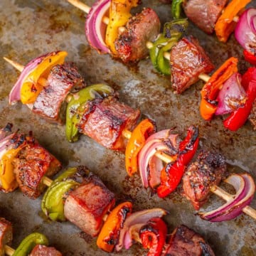 tri-tip kabobs with peppers and onions on a baking sheet