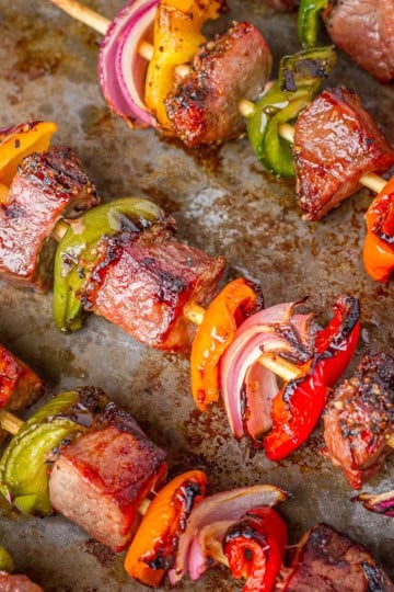 grilled tri-tip kabobs with peppers and onions on a baking sheet