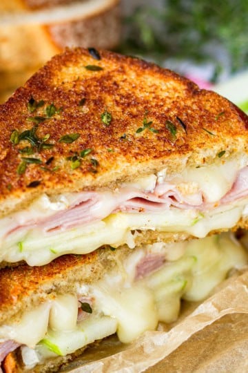 ham and brie grilled cheese sandwich with green apples on brown parchment paper