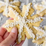 hand holding a snowflake sugar cookie piped with easy royal icing recipe and sprinkled with sugar pearls