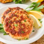 crispy fried tuna patties on white parchment paper with fresh Italian parsley and lemon wedges