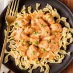 chicken paprikas recipe over egg noodles on a black ceramic plate