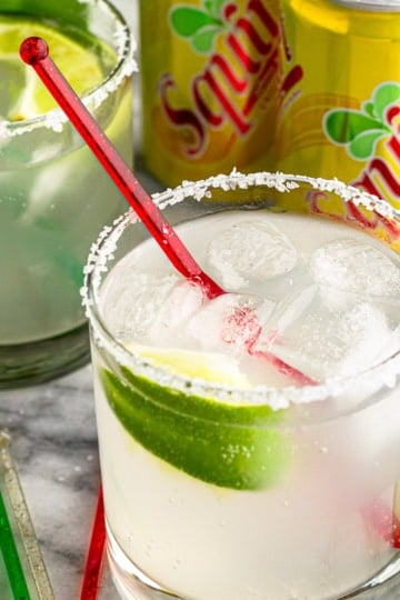 paloma drink recipe made with squirt and tequila plus limes and a pinch of salt in a highball glass with a red stir stick