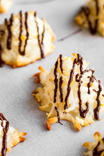 clementine coconut macaroons drizzled with chocolate on white parchment paper